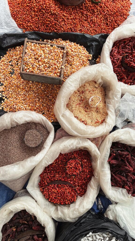 Top view of diverse spices and grains in bags at Xilitla market, México, showcasing rich textures and colors.
